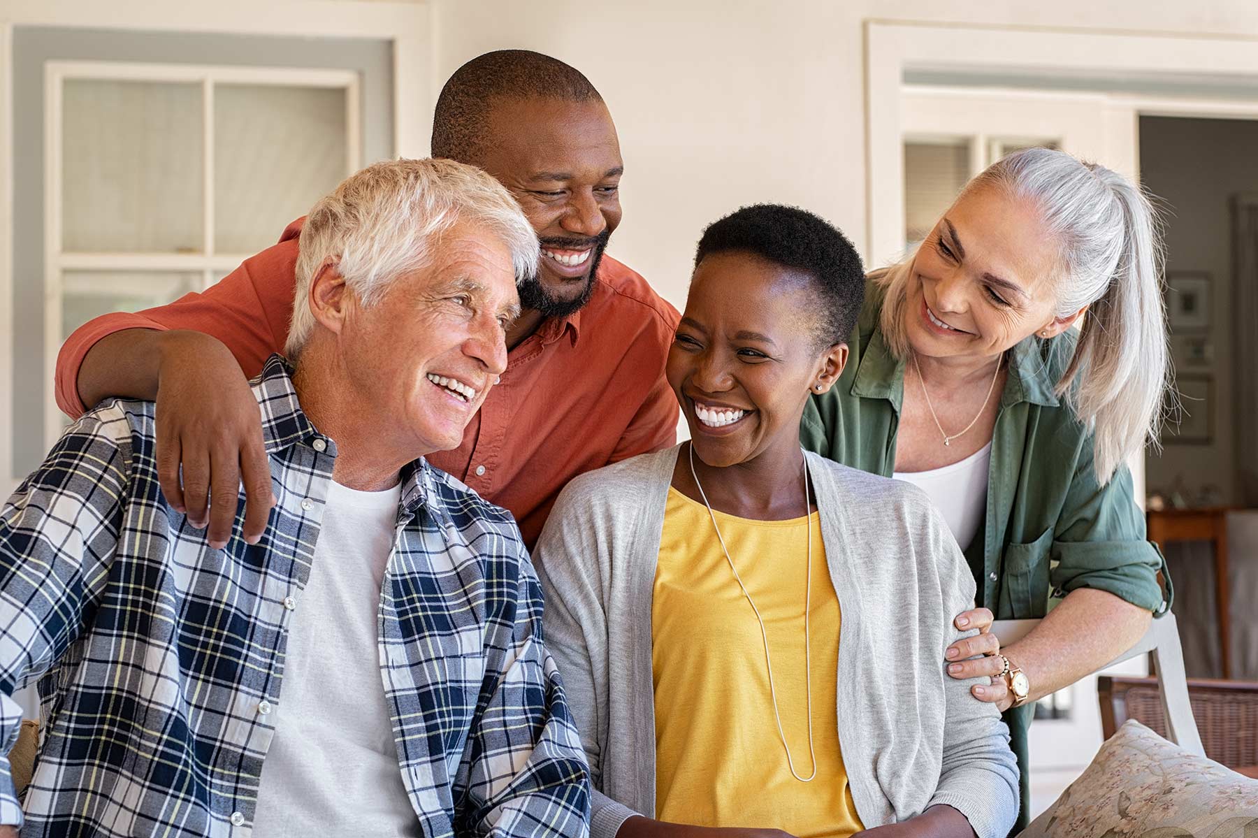 Group of middle age people on a front porch chatting.