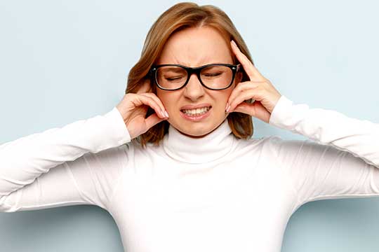 Woman holding her ears to avoid triggering sounds